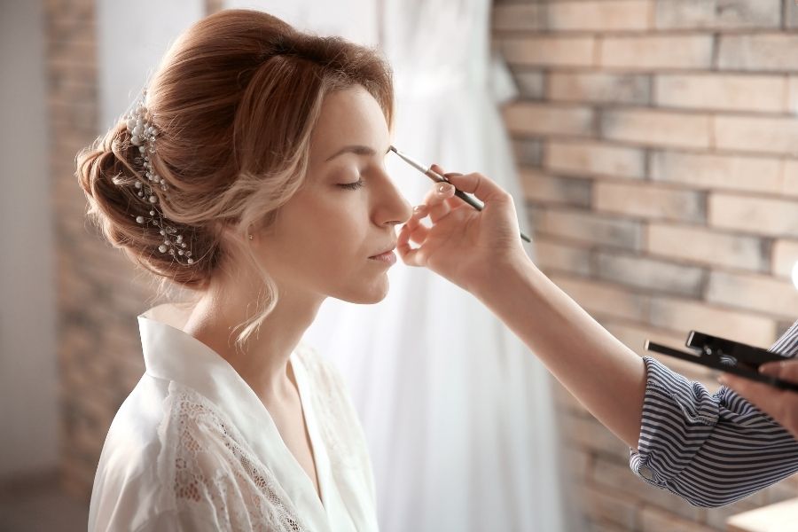 Maquillage de mariée professionnel avec application du fard à paupières par une maquilleuse experte